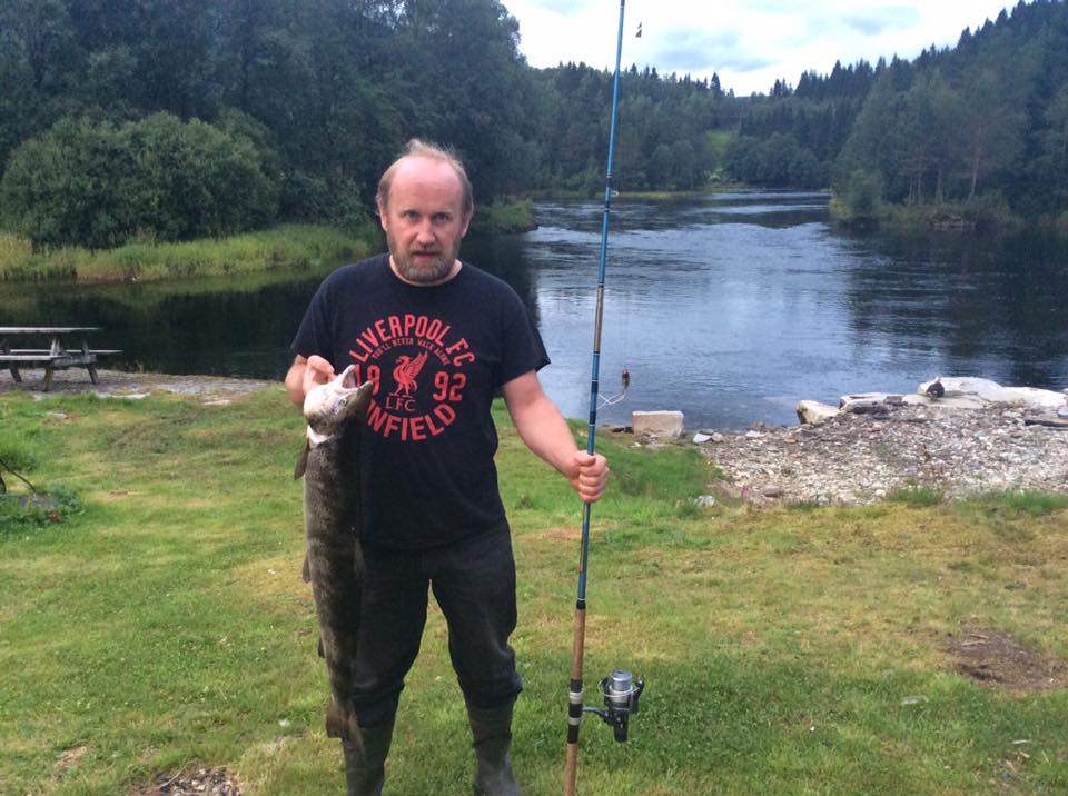 mann med fisk i hånden